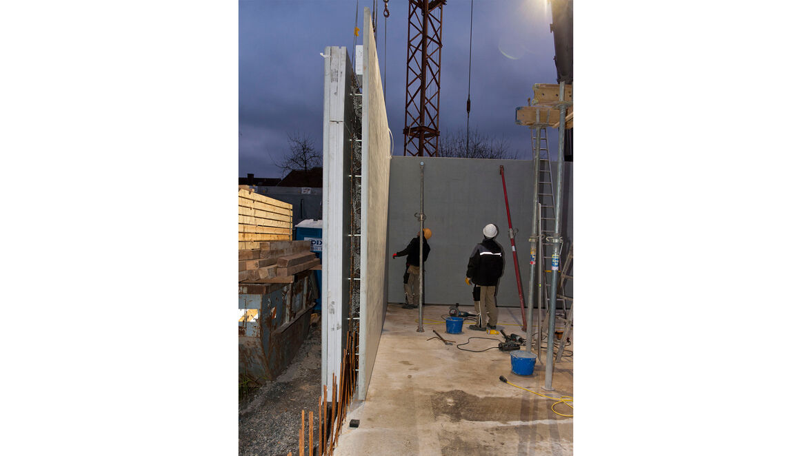 Versetzen einer Elementwand per Kran auf der Baustelle.
